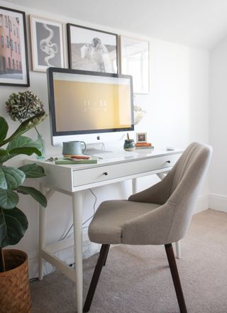 white office with gray chair, gray carpet, prints on the wall and a large plant in the corner