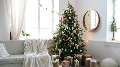 A Christmas tree in a living room surrounded by presents