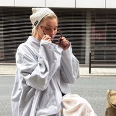 Elsa Hosk wearing a light blue trench coat, white petticoat pants, and white glove flats
