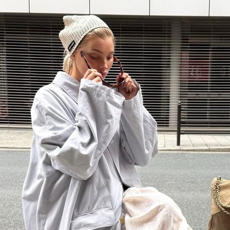 Elsa Hosk wearing a light blue trench coat, white petticoat pants, and white glove flats