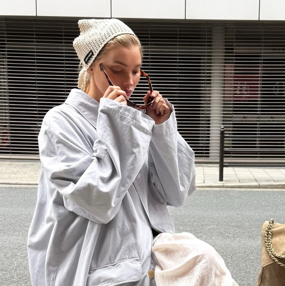 Elsa Hosk wearing a light blue trench coat, white petticoat pants, and white glove flats