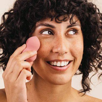 woman holding one of the best make-up sponges up to her face