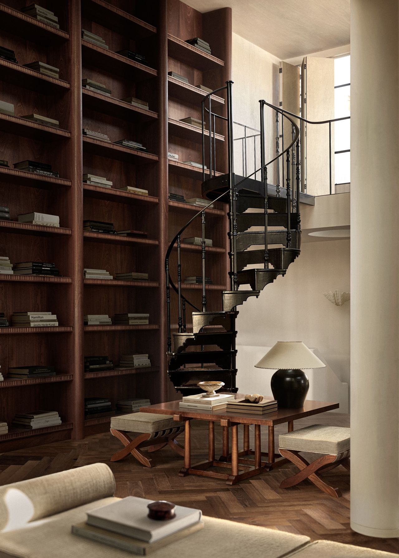 room with a bookshelf wall and a spiral staircase