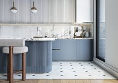 A kitchen with pastel blue cabinetry and marble countertop and backsplash