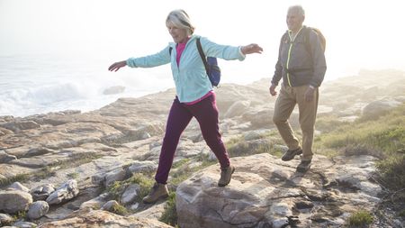 Senior couple hiking outdoors together on a coastal path near the sea