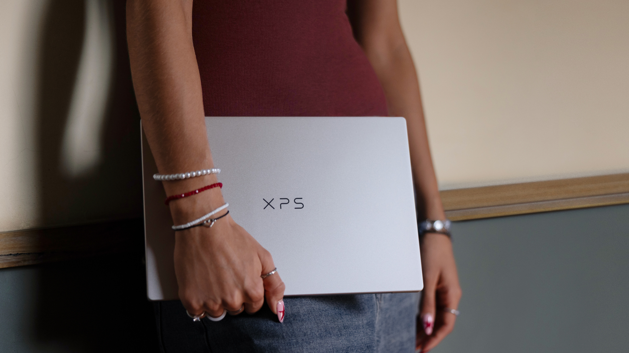 Dell XPS 13 closed laptop held in someone's hand down by their waist