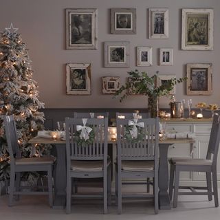 Dining room with table and chairs with framed pictures on the wall decorated for Christmas