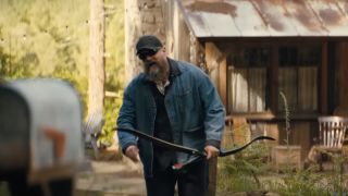 David Harbour walks towards the camera while holding a bow and arrow in A Working Man.