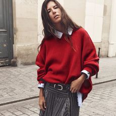 Model wearing a Free People red jumper and shirt with pinstripe skirt on a street