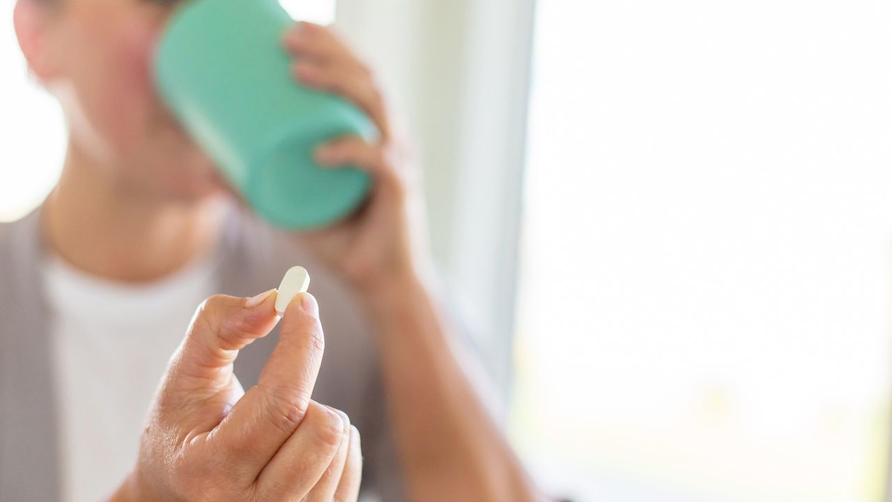 woman taking a glucosamine supplement with water