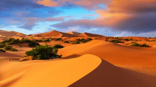 A photo of the desert with three large star dunes in the distance