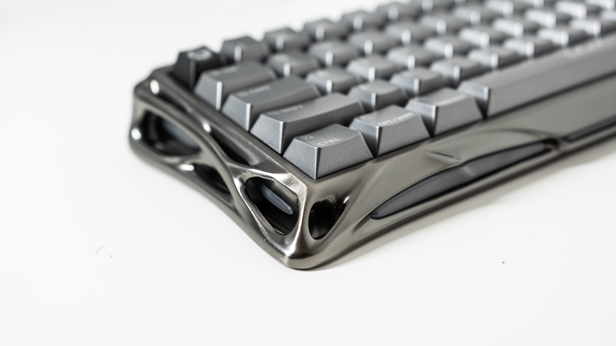 A Gravastar Mercury V60 Pro gaming keyboard with a shiny aluminium shell on a white desk.