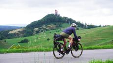 Image shows Anna cycling towards Banská Štiavnica while on a gravel bikepacking trip in Central Europe.
