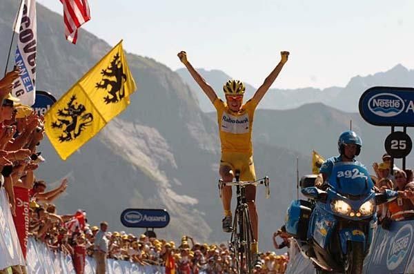 Rasmussen crosses the line no hands, on an uphill.