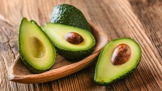 Two avocados in a bowl each cut in half