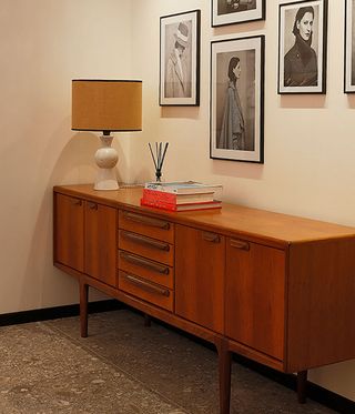 Wooden side table with lamp and frames on the wall