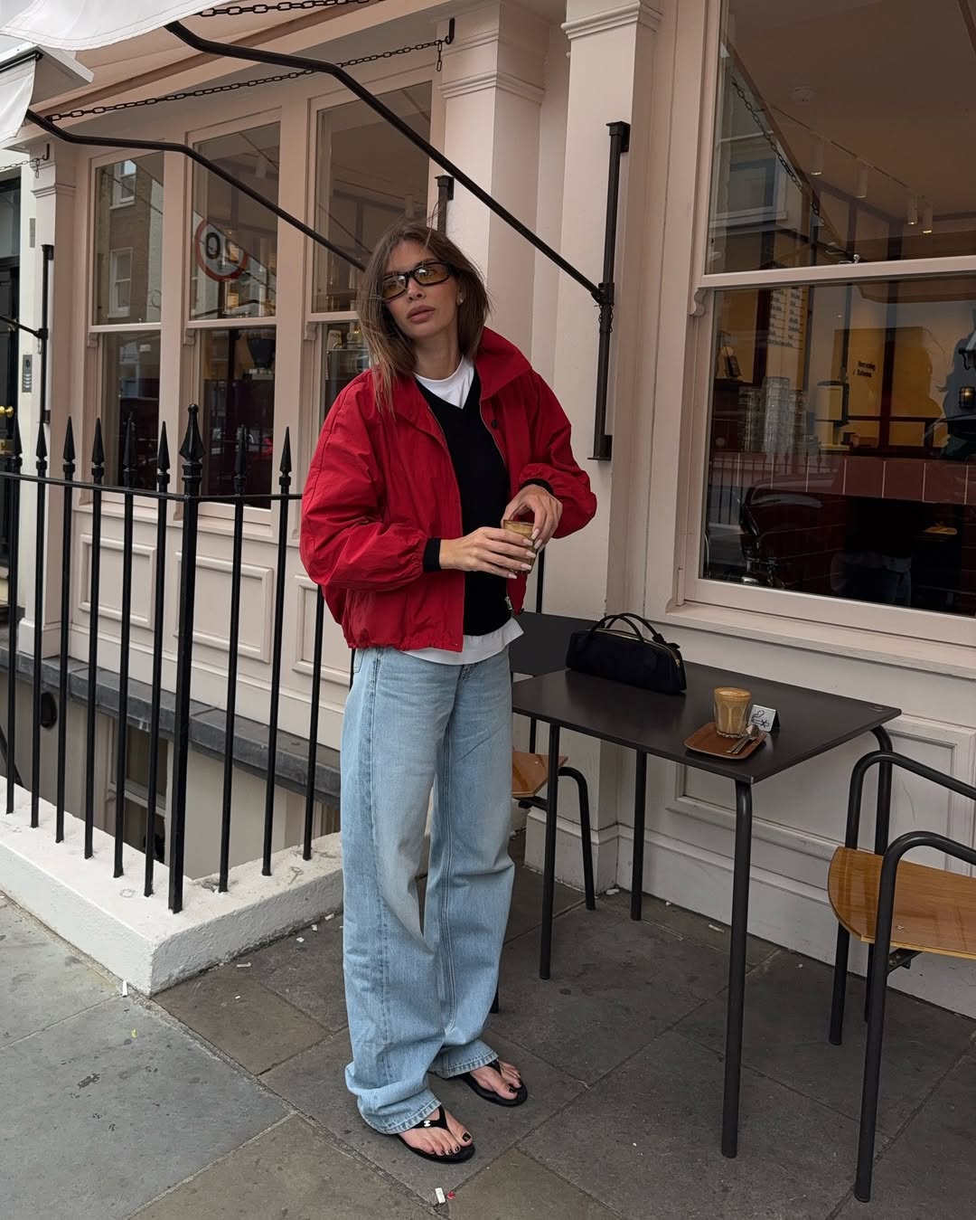 Influencer Eva Saeed wearing a red bomber jacket, straight jeans and flip flops.