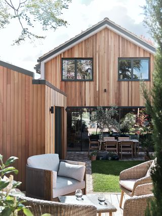wood clad exterior of a midcentury style home with double doors onto the garden and garden seating