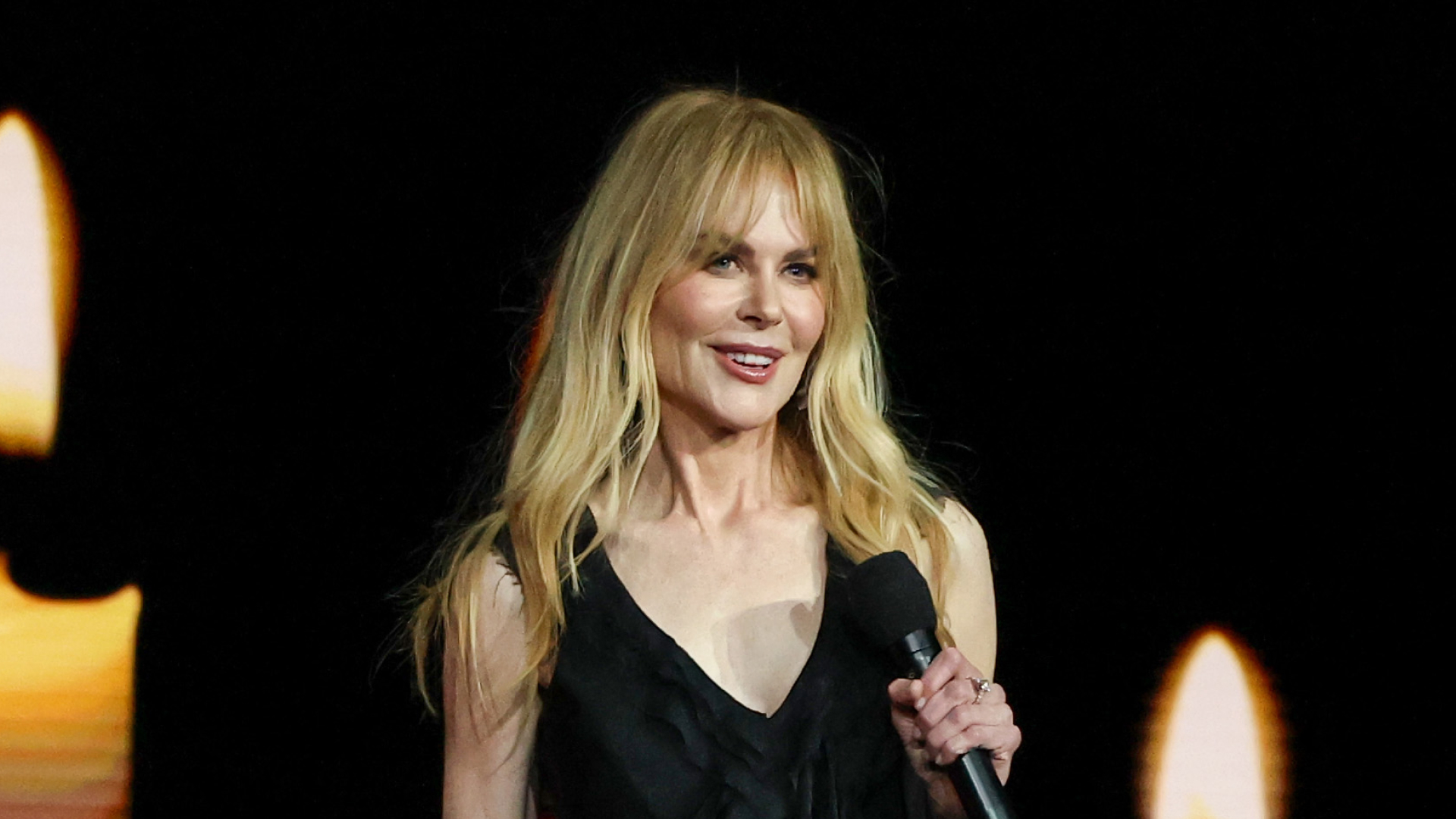 Nicole Kidman has long blonde hair and bangs and wears a slinky black gown to promote 'Practical Magic' with Sandra Bullock
