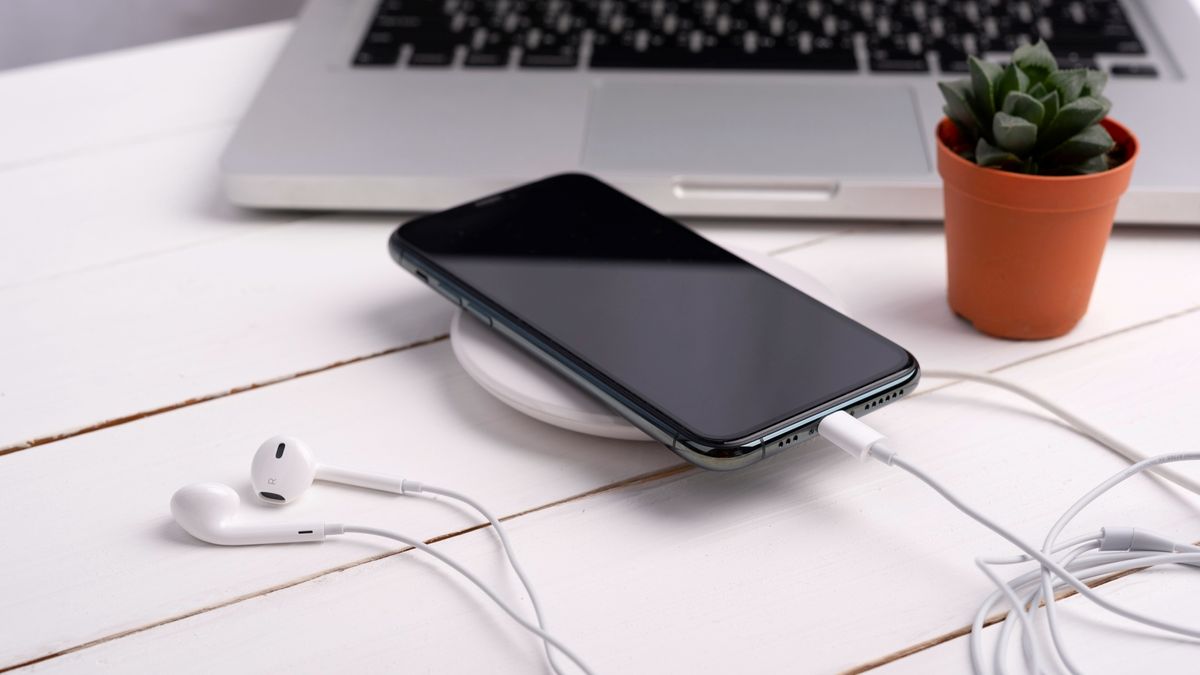 A phone being charged on a wireless charging pad on a desk