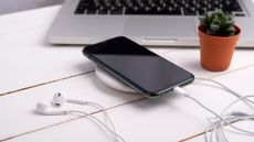 A phone being charged on a wireless charging pad on a desk