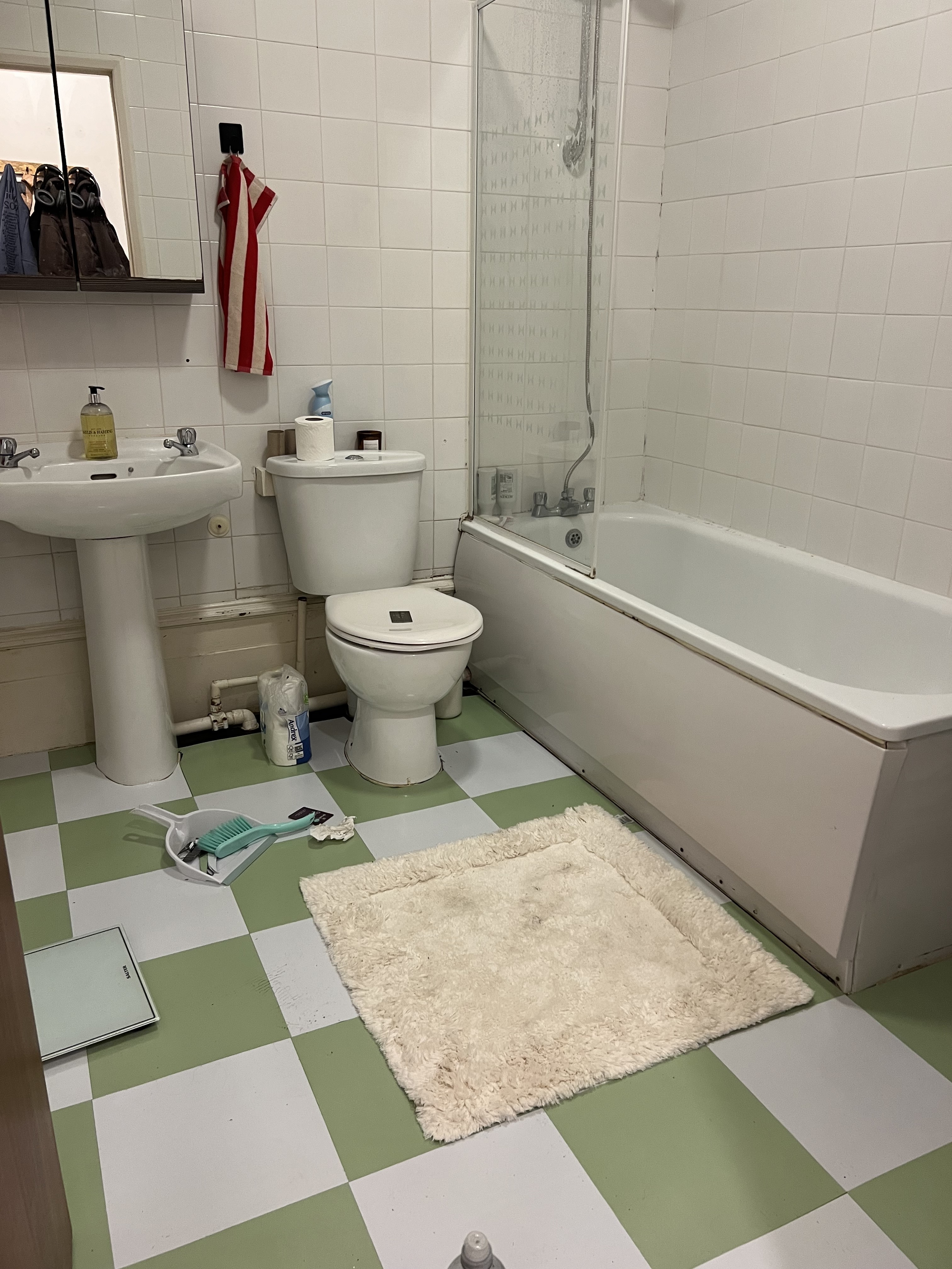 a bathroom with all white appliances, light green and white peel-and-stick tiles on the floor and a white fluffy rug.