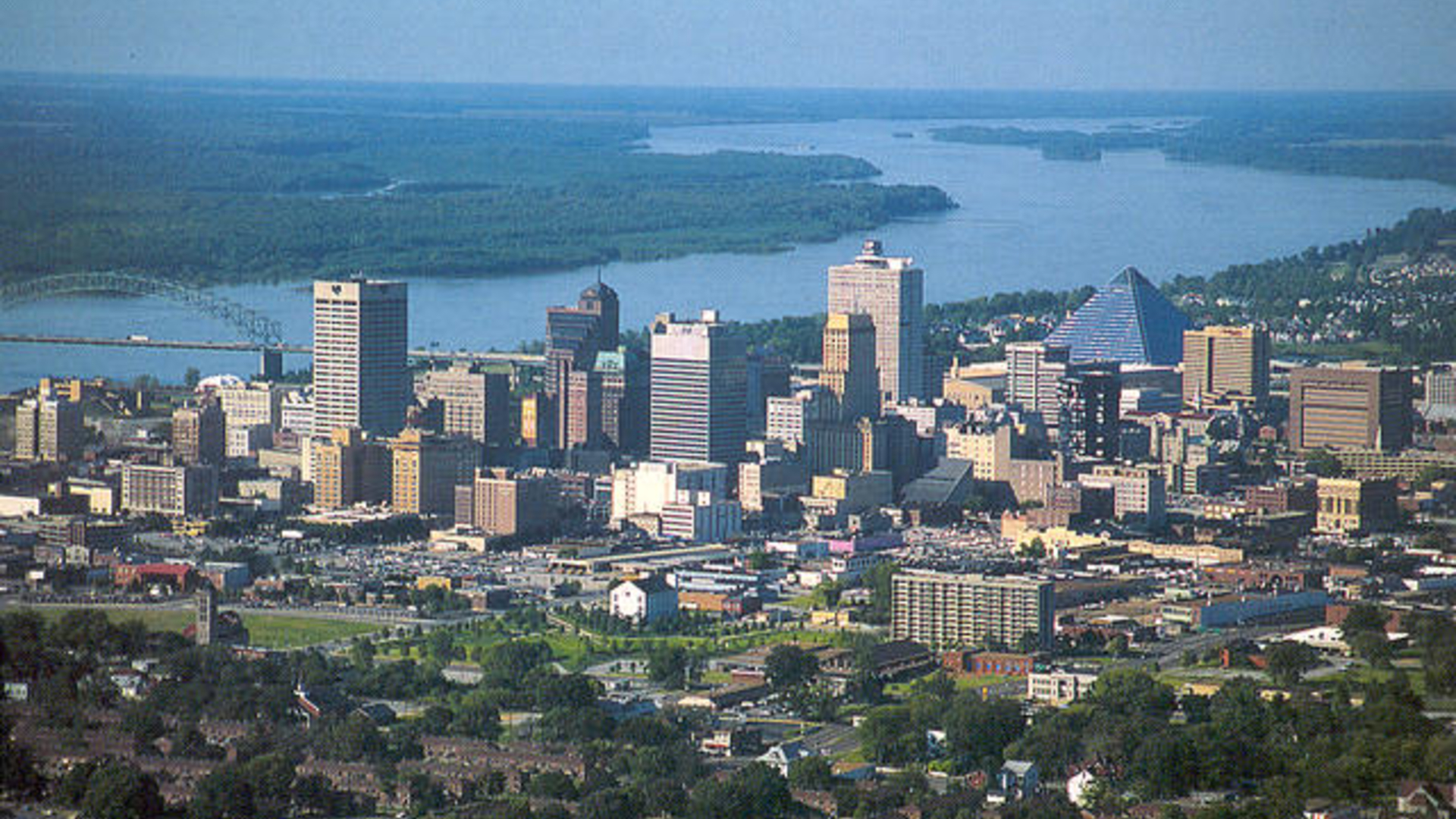 An urban city with lots of tall buildings and skyscrapers sits next to a winding river