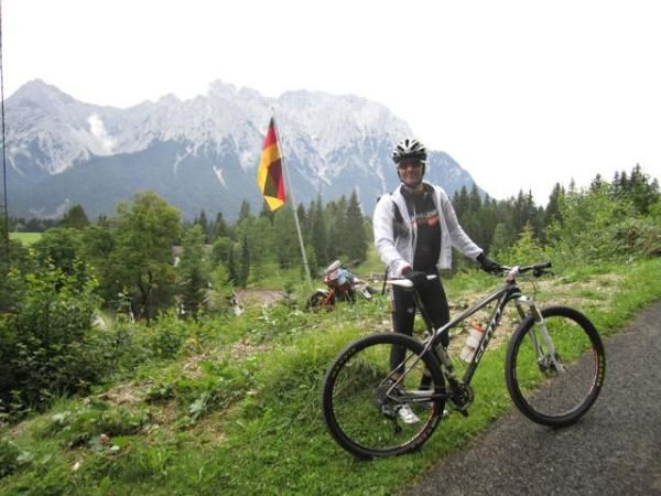 Brandon stands in front of the German flag and German Alps.
