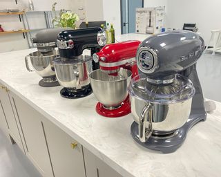 Image of best stand mixers review process with four stand mixers on marble countertop