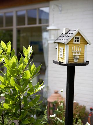 bird house design ideas: yellow and white house on stand