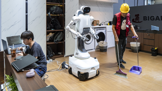 a person sweeping the floor in front of a robot