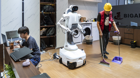 a person sweeping the floor in front of a robot