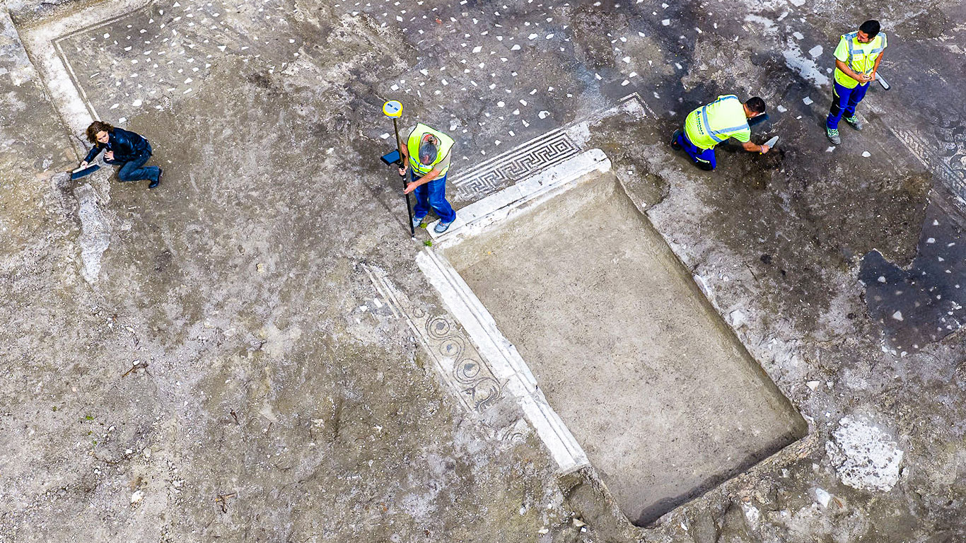 archaeologists work at an ancient Roman site revealing mosaic floors and frescoed walls of a villa