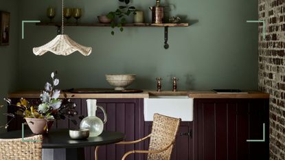 dark green colored kitchen with black painted cabinets to show daring paint color ideas for kitchen cabinets