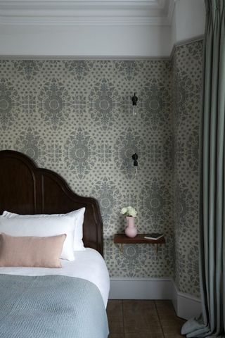 small wallpapered bedroom with floating shelf