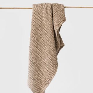 Waffle Bath Towel hanging from a rail against a white wall.