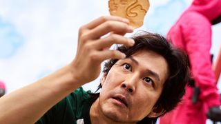 Lee Jung-jae as Seong Gi-hun holding up a piece of candy during the Netflix show, Squid Game.