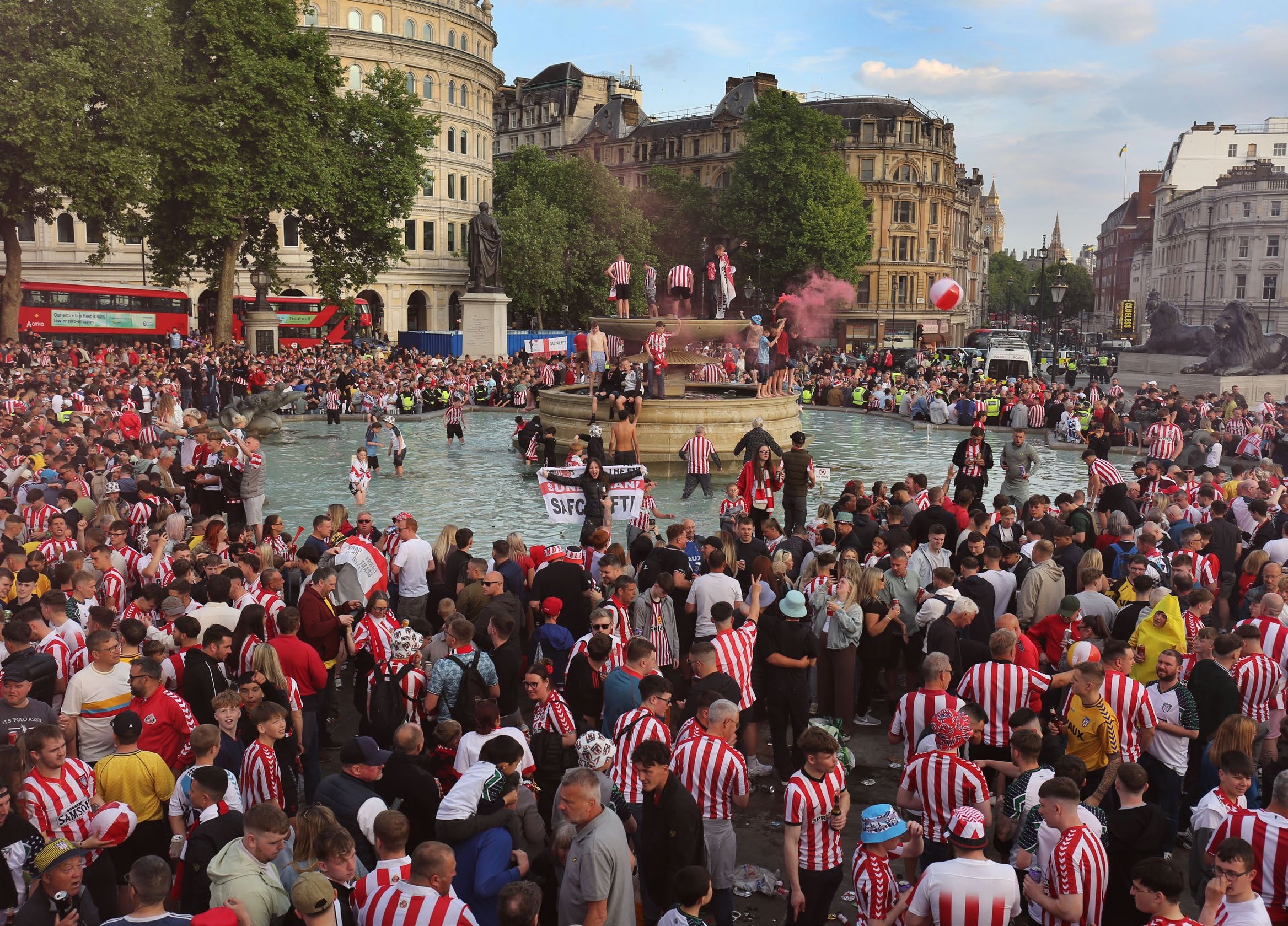 LONDON, UNITED KINGDOM - 2025/05/23: Crowds of Sunderland fans pack in to Trafalgar Square to celebrate finding themselves playing one match to get into the Premiership. Sunderland fans fill Trafalgar Square to celebrate and gather before their championship play off final against Sheffield United at Wembley tomorrow (Saturday 24th). The fans engaged in good humoured chanting, drinking and letting off of red and white smoke flares ahead of their big day. The winner of the game gets the third and final promotion place into the 2025-2026 Premiership league and the extra revenue that comes with it. (Photo by Martin Pope/SOPA Images/LightRocket via Getty Images)