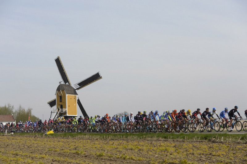 The peloton passes by a wind mill