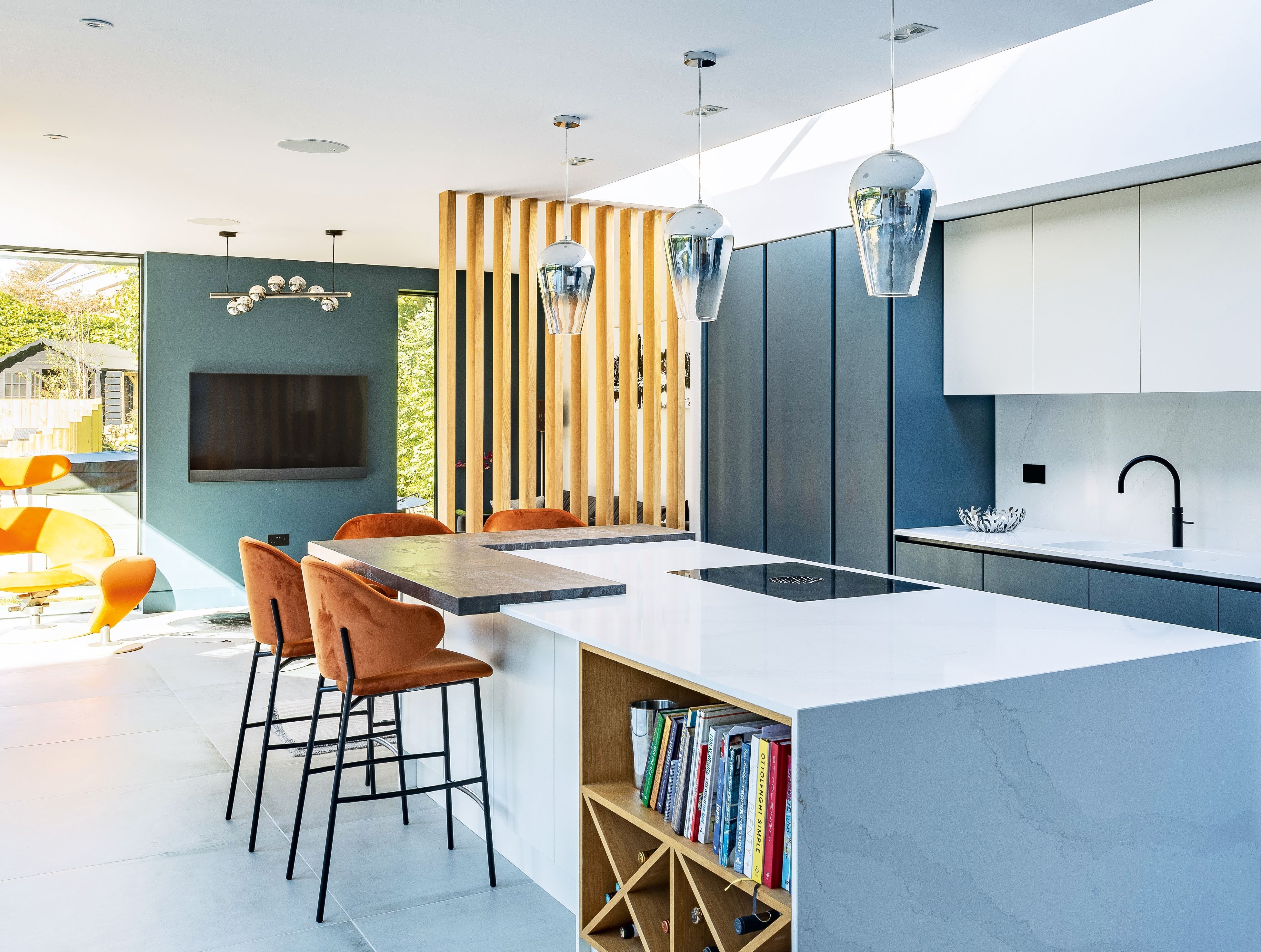 A slatted oak divider creates an element of warmth while zoning off the TV area from the kitchen