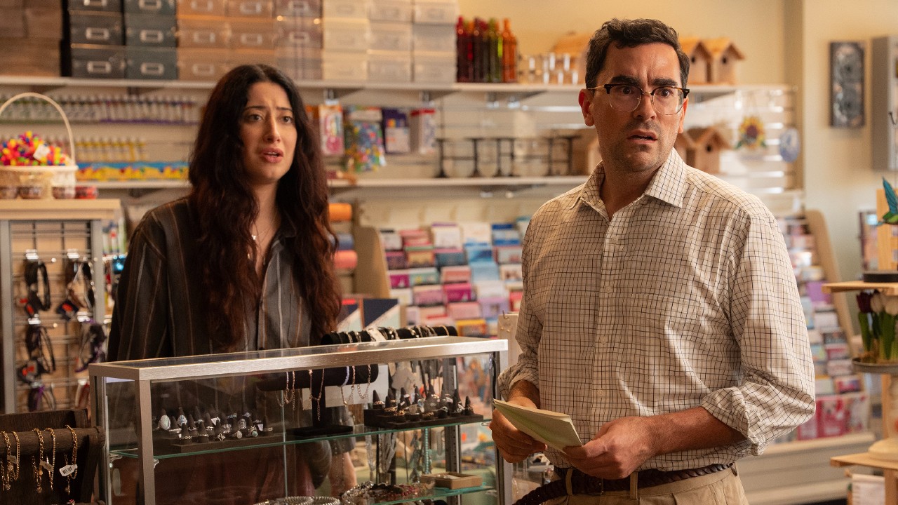 L to R) Taylor Ortega as Morgan and Dan Levy as Nicky standing in a story by a jewlery case.