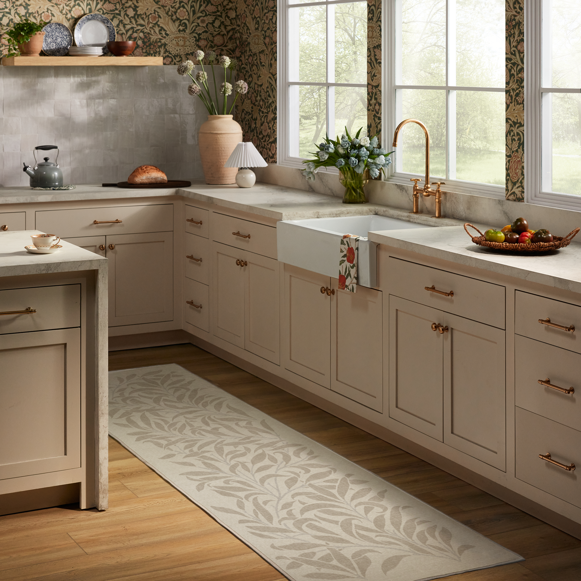 A pale pink kitchen with Morris & Co print rug on the wooden floor