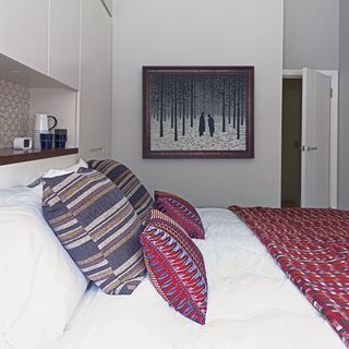 guest bedroom with cushions on bed and frames on wall