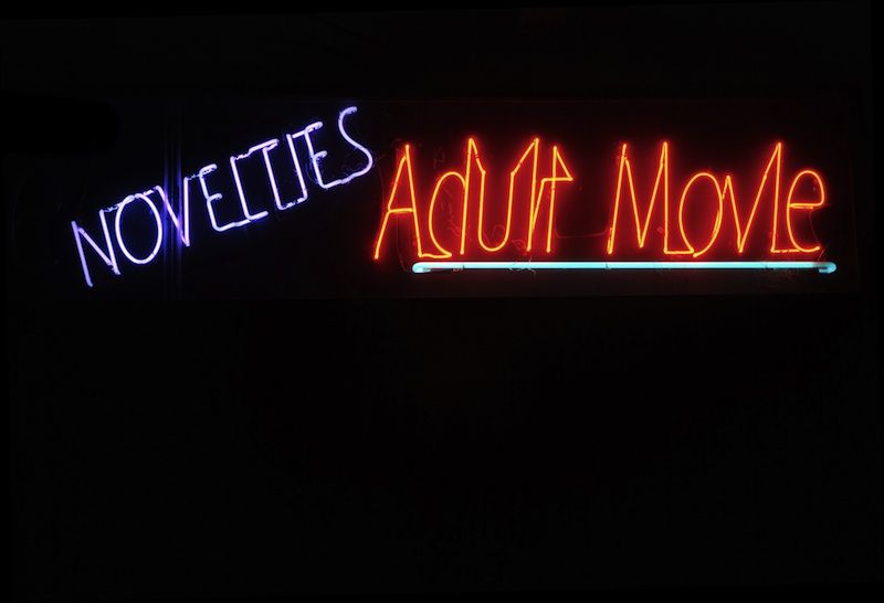 Neon adult video sign at night.