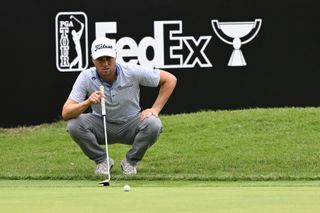 Justin Thomas lines up a putt in front of a FedEx Cup logo