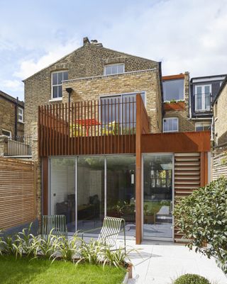 a corten wrap around kitchen extension with a balcony