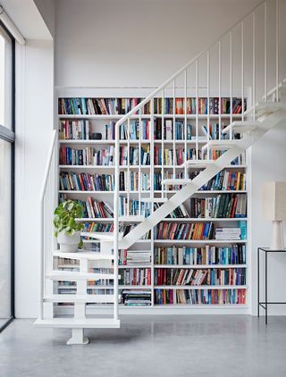 white staircase with bookshelf wall