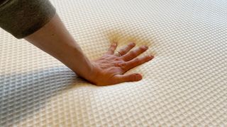 A hand pressing down on the Nectar Premier Hybrid mattress