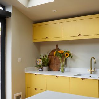 a modern yellow kitchen with white worktop