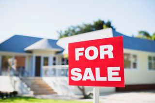 A For Sale sign in front of a white house